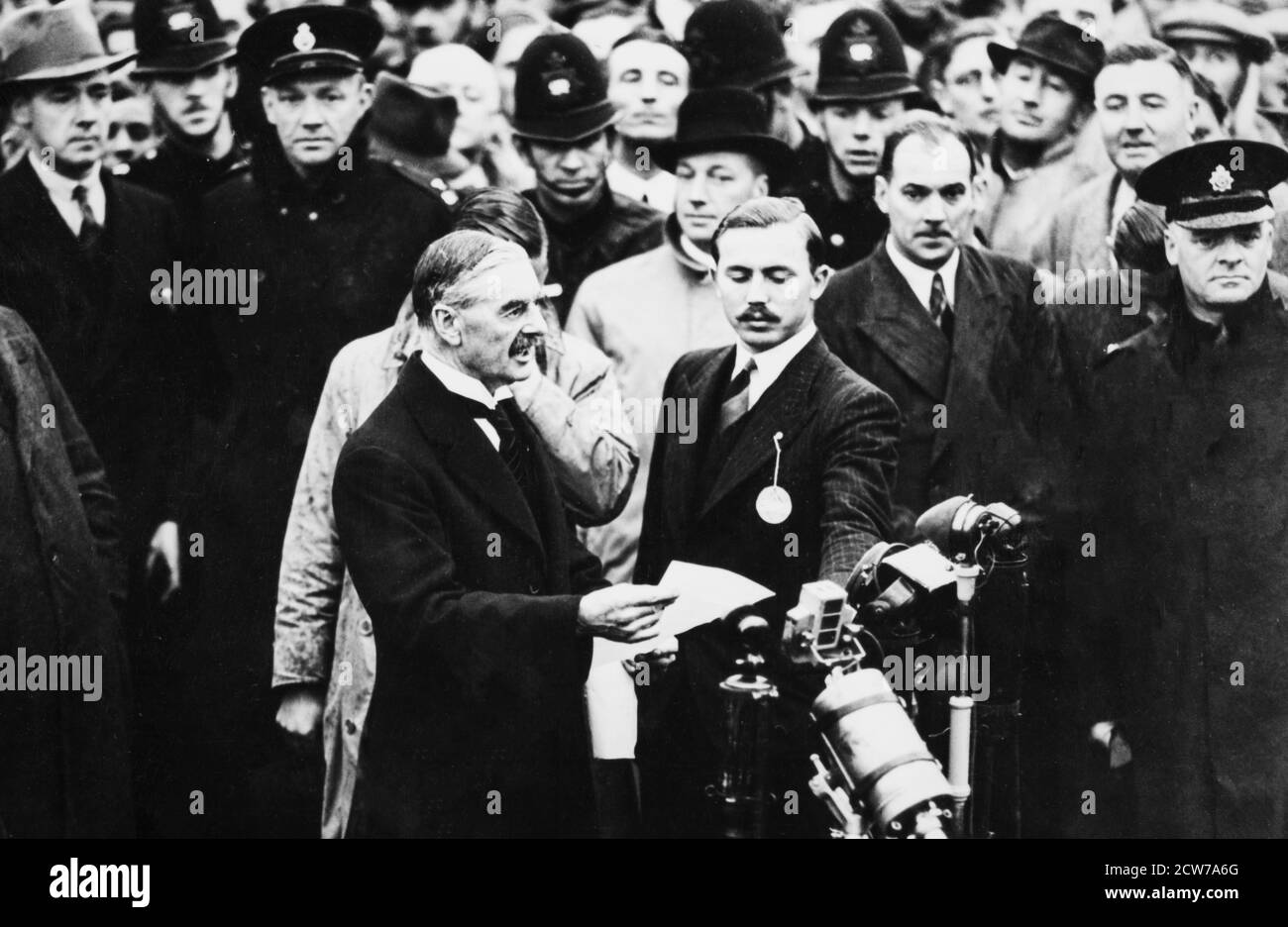 AÉRODROME DE HESTON, LONDRES - SEPTEMBRE 30 : Neville Chamberlain, Premier ministre britannique, arrive à l'aérodrome de Heston, Londres, après une rencontre avec Adolf Hitler, le 30 septembre 1938. Il agita un morceau de papier, déclarant que nous avons « la paix pour notre temps », cherchant à éviter la guerre en Europe, les dirigeants de Grande-Bretagne, de France et d'Italie signèrent le Pacte de Munich, acceptant les demandes d'Hitler et cédant la Tchécoslovaquie à l'Allemagne. Banque D'Images