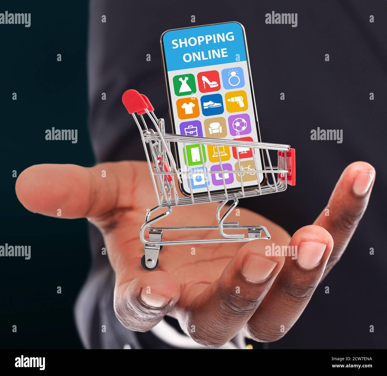Un gars noir tenant un panier avec un téléphone mobile, collage avec un magasin onilne vendant différents articles ménagers à l'écran Banque D'Images