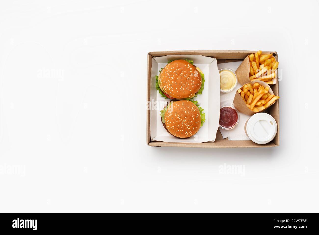 Déjeuner rapide moderne pour deux. Hamburger et cheeseburger, ketchup et sauce dans des récipients, frites dans des sacs en papier et tasse de café dans une boîte Banque D'Images