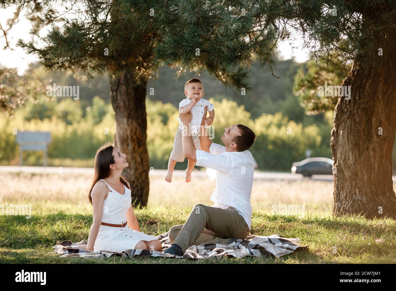 maman, papa lève son bébé garçon en plein air et regarde son sourire.  Parents heureux de passer du temps à jouer avec son fils dans le parc le  jour de l'été. Sélectif