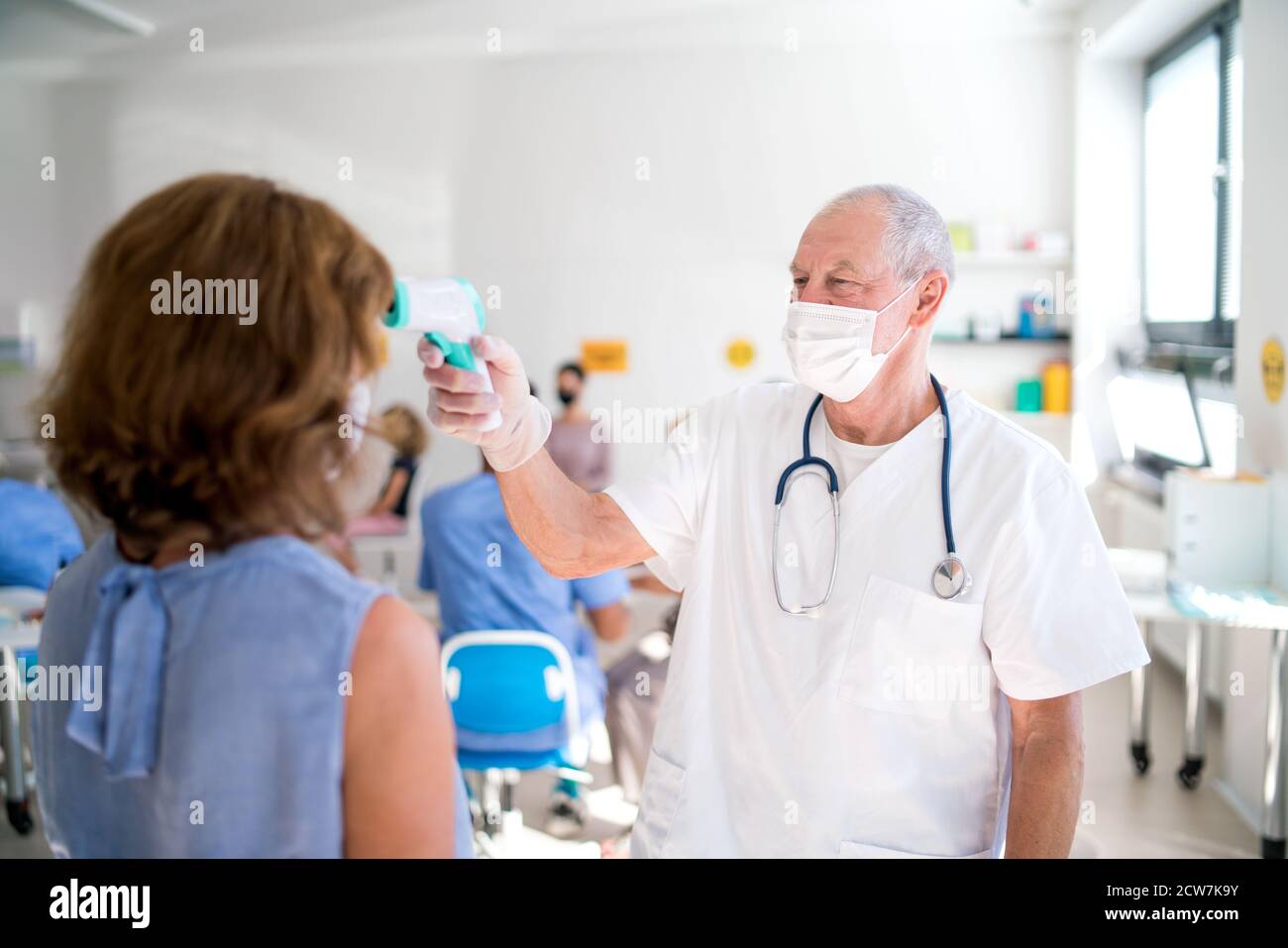 Médecin avec masque facial mesurant la température, coronavirus, covid-19, mesurant la température et concept de vaccination. Banque D'Images
