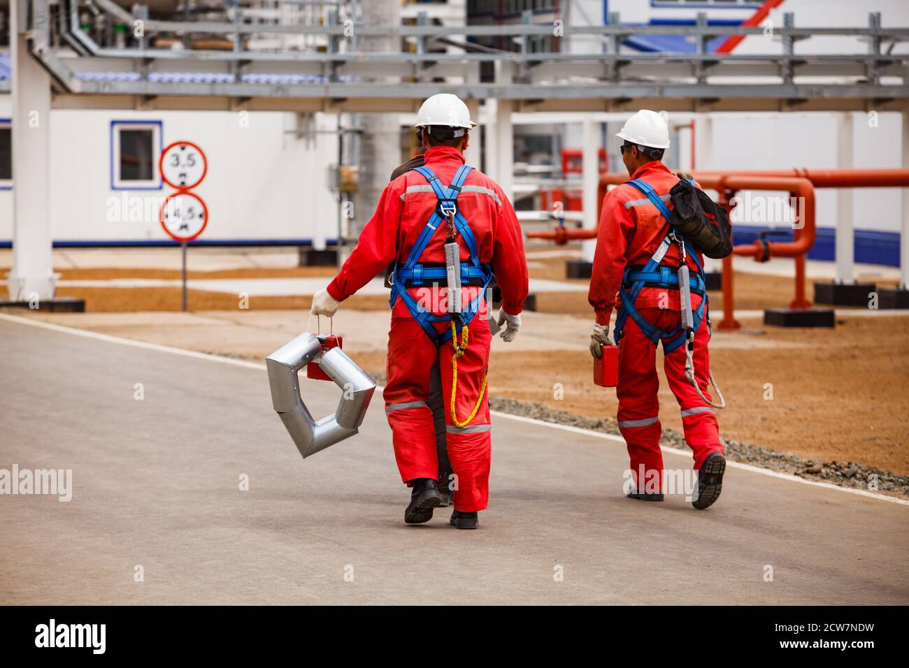 Raffinerie de pétrole et usine de traitement du gaz. Deux grimpeurs industriels en vêtements de travail rouges et casques blancs. Gisement de pétrole de Zhaik-Munai, Kazakhstan. Banque D'Images