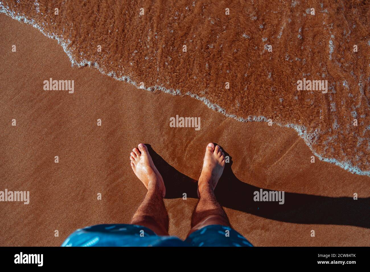 Mans pieds dans l'eau claire on beach Banque D'Images