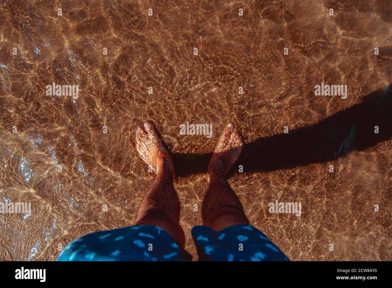 Mans pieds dans l'eau claire on beach Banque D'Images