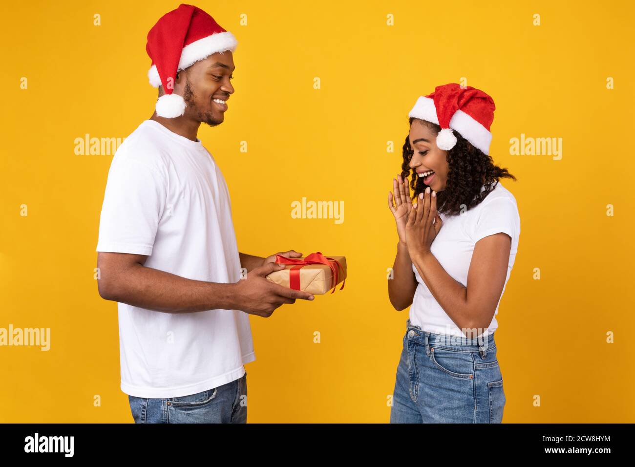 Boyfriend noir donnant un cadeau de Noël à une petite amie sur fond jaune  Photo Stock - Alamy