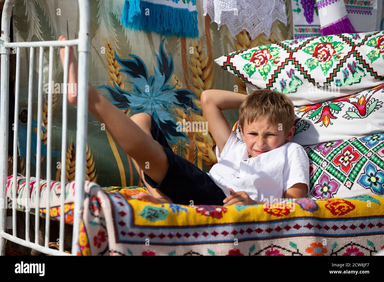 Enfant russe ou ukrainien sur un vieux lit ethnique avec oreillers et  couvre-lits brodés avec un motif slave. Bélarussien garçon Photo Stock -  Alamy