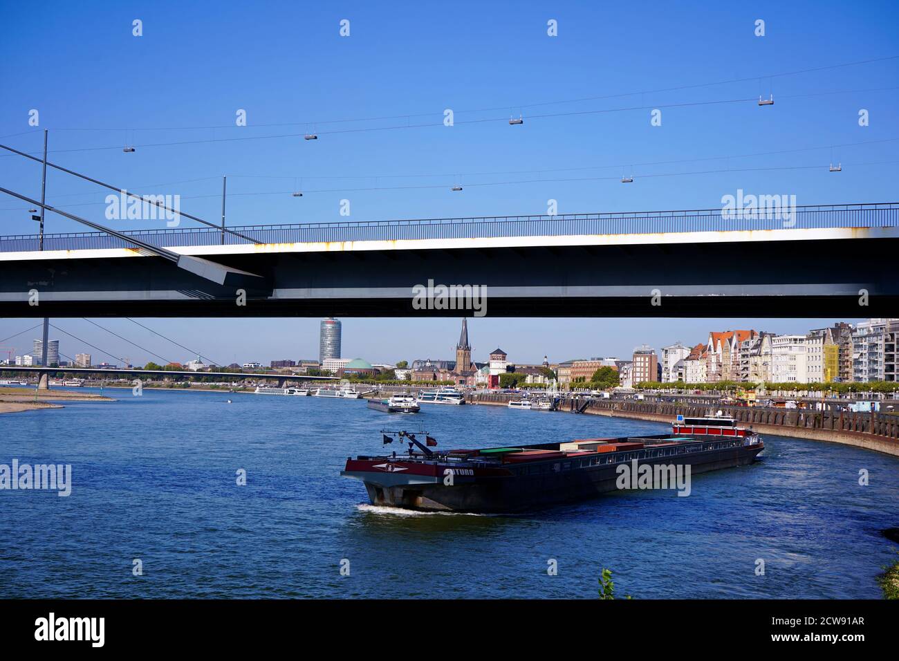 Vue sur le Rhin à Düsseldorf avec un bateau passant sous le pont Rheinnnie. Banque D'Images