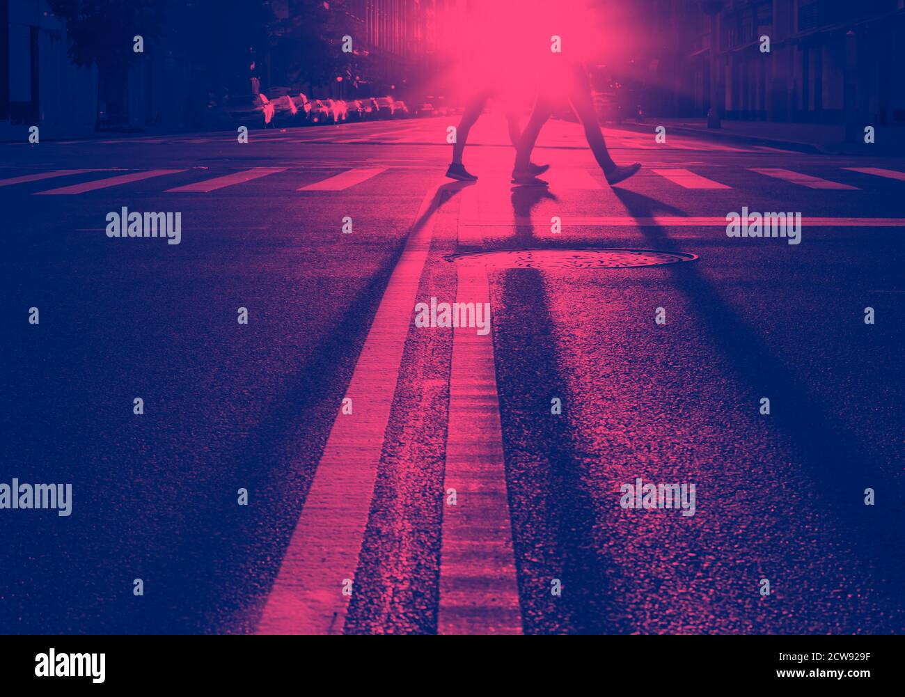 Homme et femme marchant de l'autre côté de la rue à New York Ville avec la lumière du coucher de soleil jetant de longues ombres dedans effet rose et bleu Banque D'Images