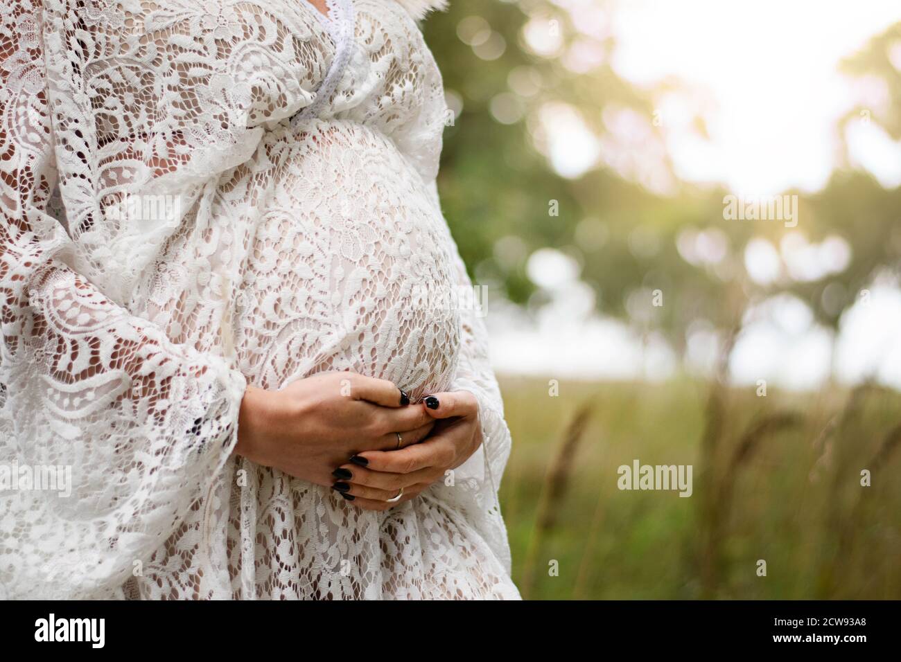 J'espère qu'un bébé viendra bientôt. Gros plan d'une femme enceinte dans  une belle robe bohème chic tenant son ventre à l'extérieur pendant le  coucher du soleil Photo Stock - Alamy