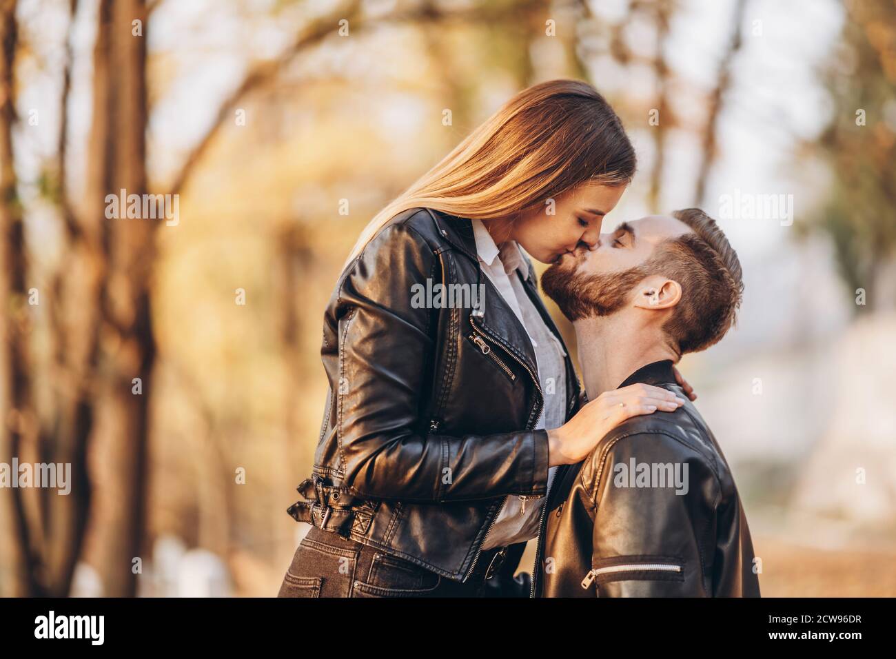 Un jeune couple s'embrasse sur le fond du parc d'automne. Un homme a