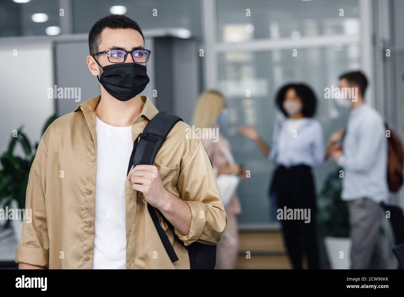 Pandémie et travail de bureau avec les gens concept. Concentrez-vous sur l'homme millénaire dans un masque de protection et des lunettes avec sac à dos regardant sur le côté Banque D'Images