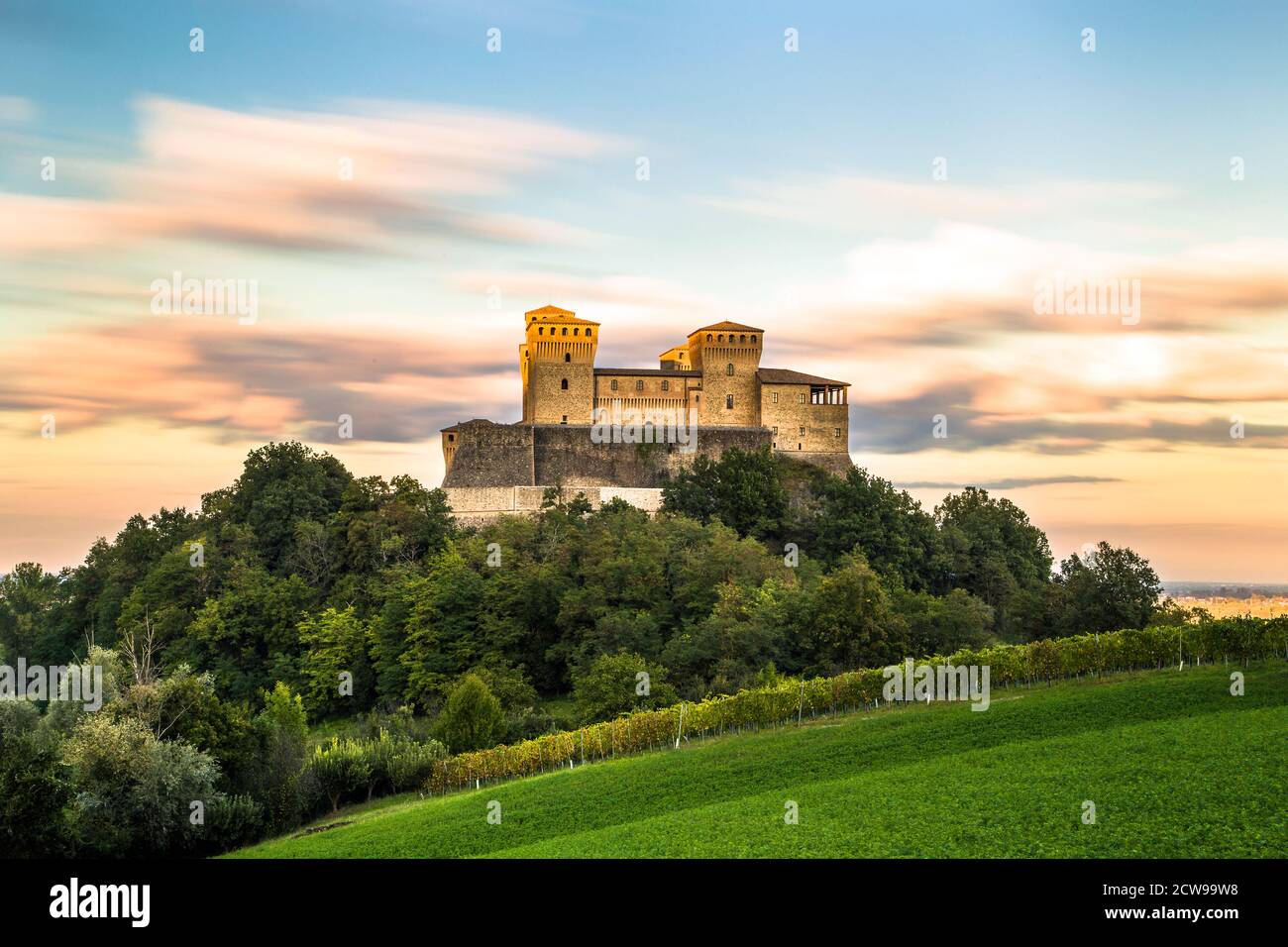 Vue longue exposition unique sur le château de Torrechiara au sommet d'un champ de vignes vertes pendant un coucher de soleil nuageux, Parme, Italie Banque D'Images