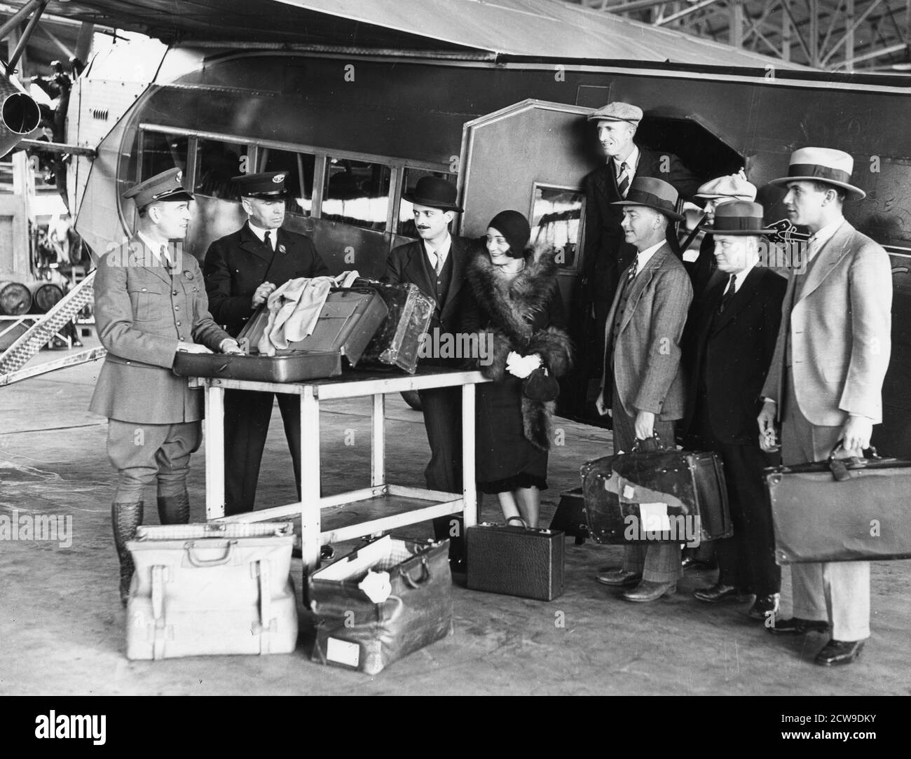 Les inspecteurs des douanes vérifient les bagages des passagers lorsqu'ils débarquent d'un Fokker F-10 exploité par Western Air Express, Alhambra, CA, 1929. (Photo de Western Air Express/PhotoQuest/RBM Vintage Images) Banque D'Images