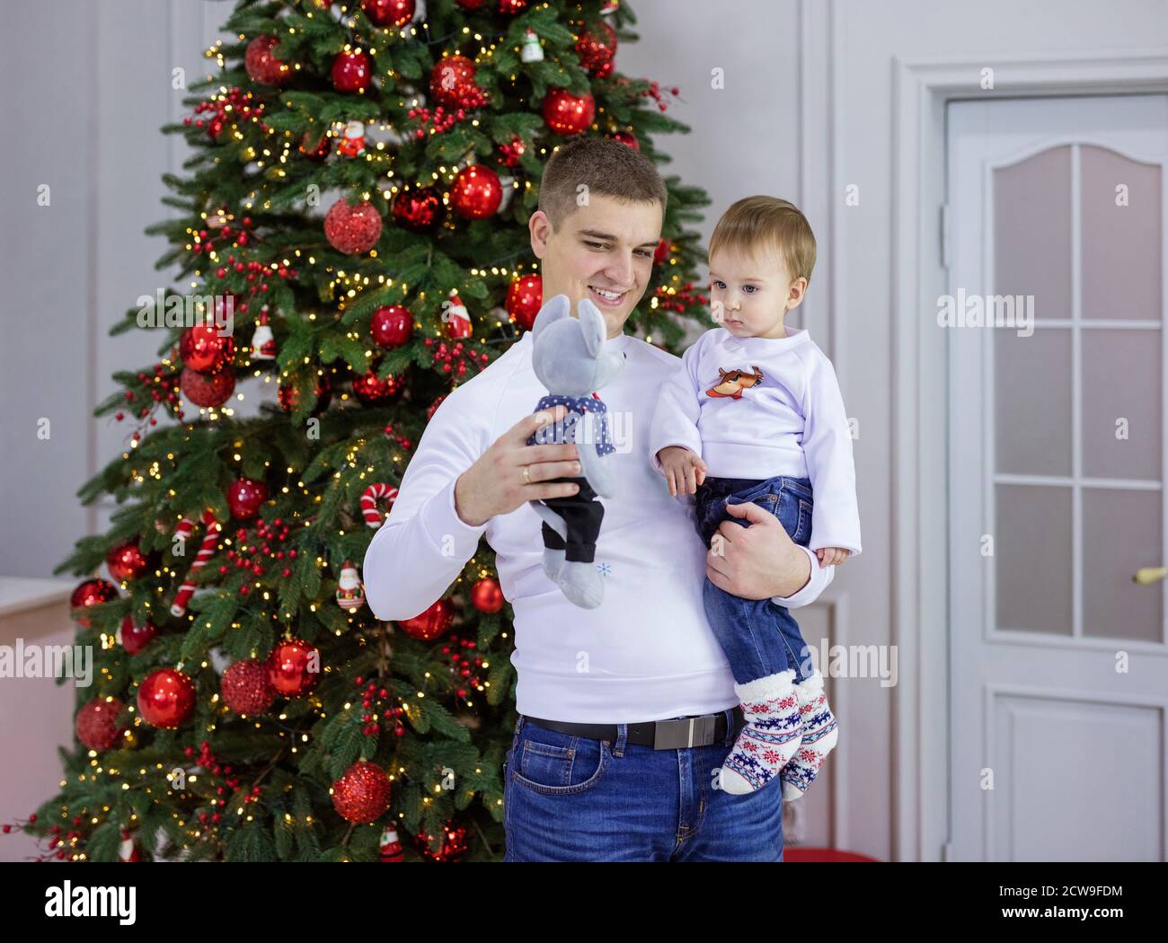 Le jeune homme caucasien et son bébé fils jouant avec le jouet Souris à l'arbre de Noël à la maison Banque D'Images