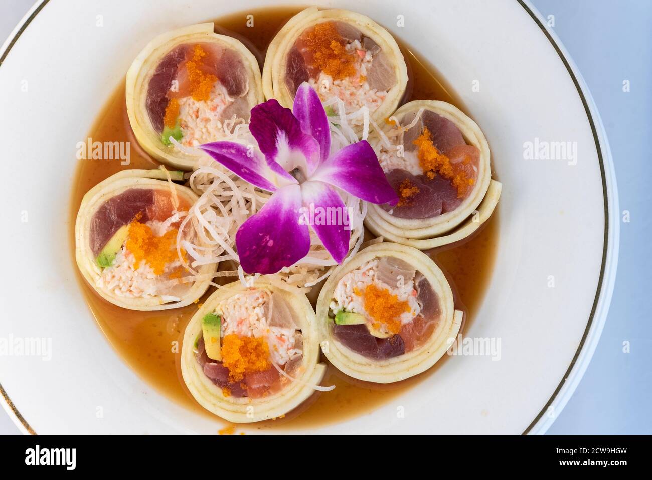 Vue en hauteur d'un assortiment de poissons crus disposés en rouleau de suhshi enrobé de concombre délicatement présenté sur une assiette à manger. Banque D'Images