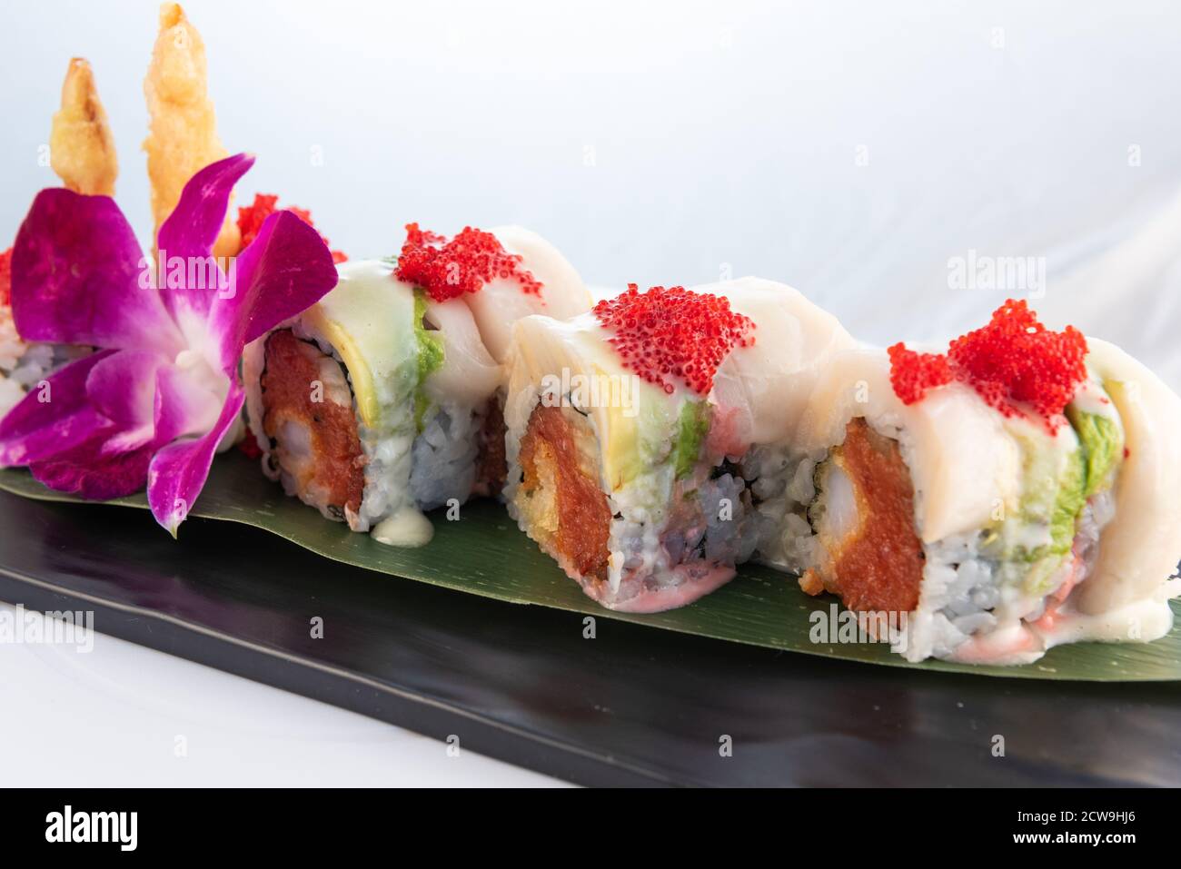 Roulé de sushi artistique avec du thon épicé et de la viande de crabe frite délicatement présentée sur une assiette à manger. Banque D'Images