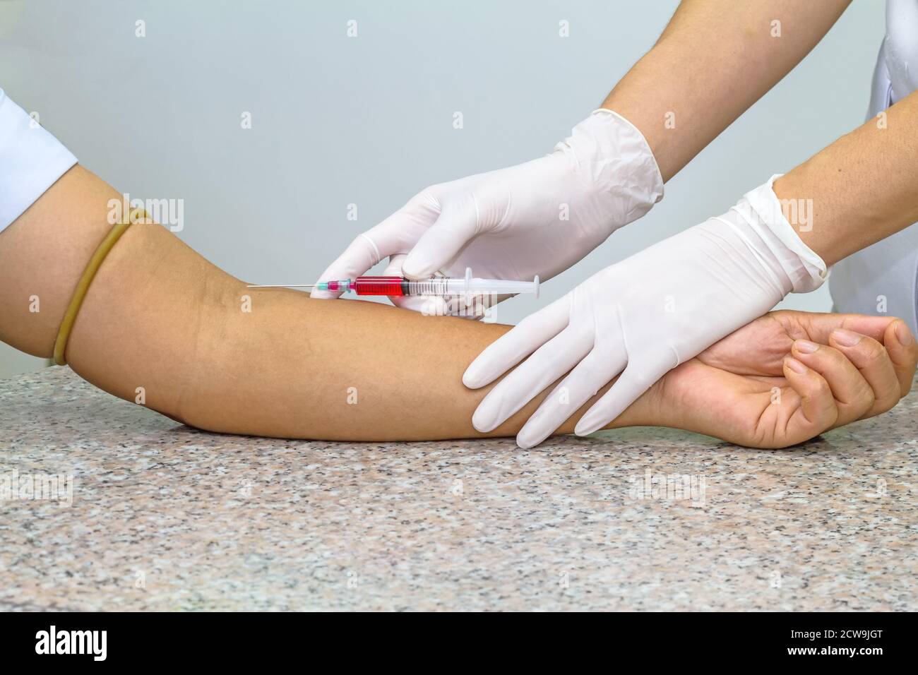 Test sanguin de la veine veineuse du patient par un médecin féminin en gants médicaux blancs sur la table en marbre Banque D'Images