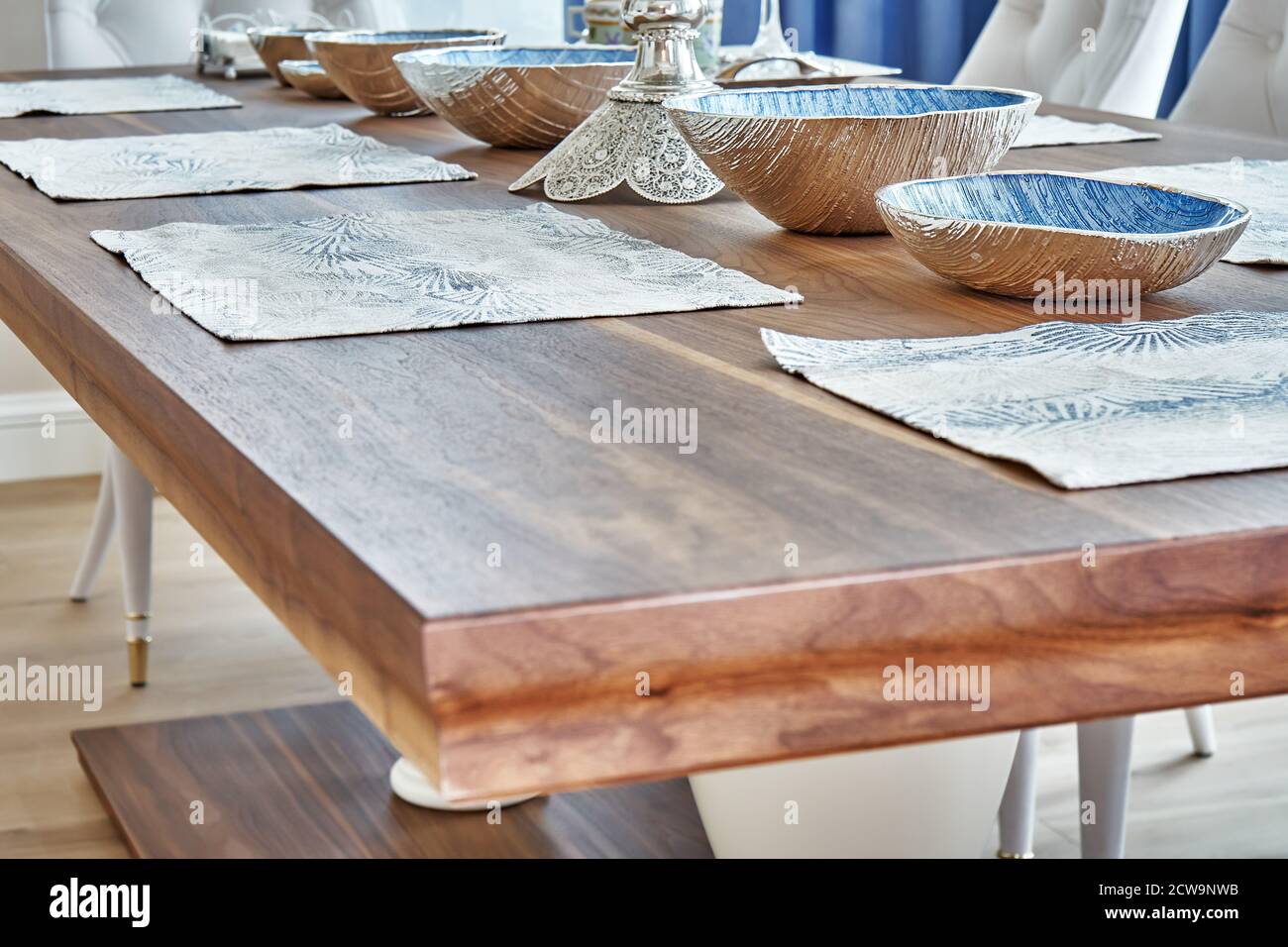 Détail de la table en bois de noyer massif sur les jambes massives et servi avec des assiettes. Se concentrer sur l'arrière-plan Banque D'Images