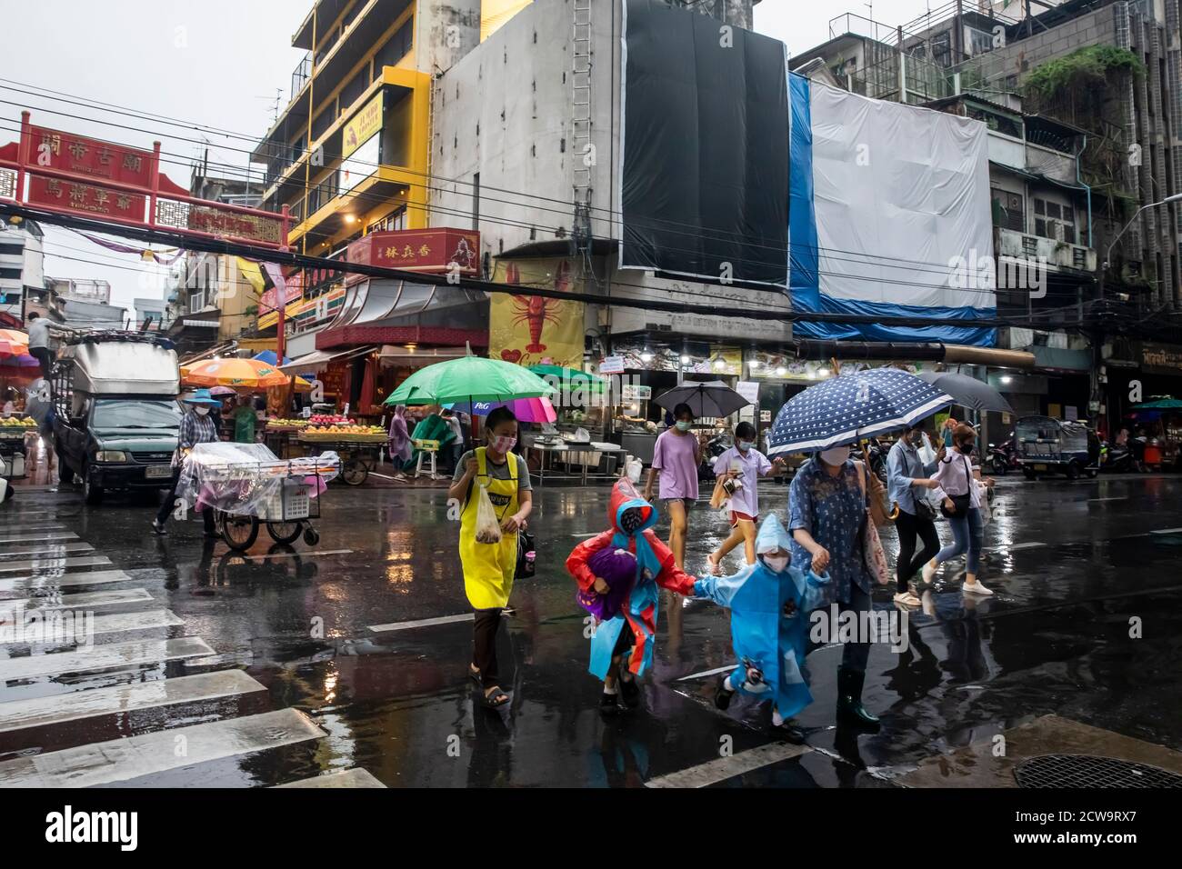 Les parents et les petits enfants s'amusent dans la rue sous la pluie pour faire la lumière verte lors d'une journée de pluie dans le quartier chinois de Bangkok. Banque D'Images