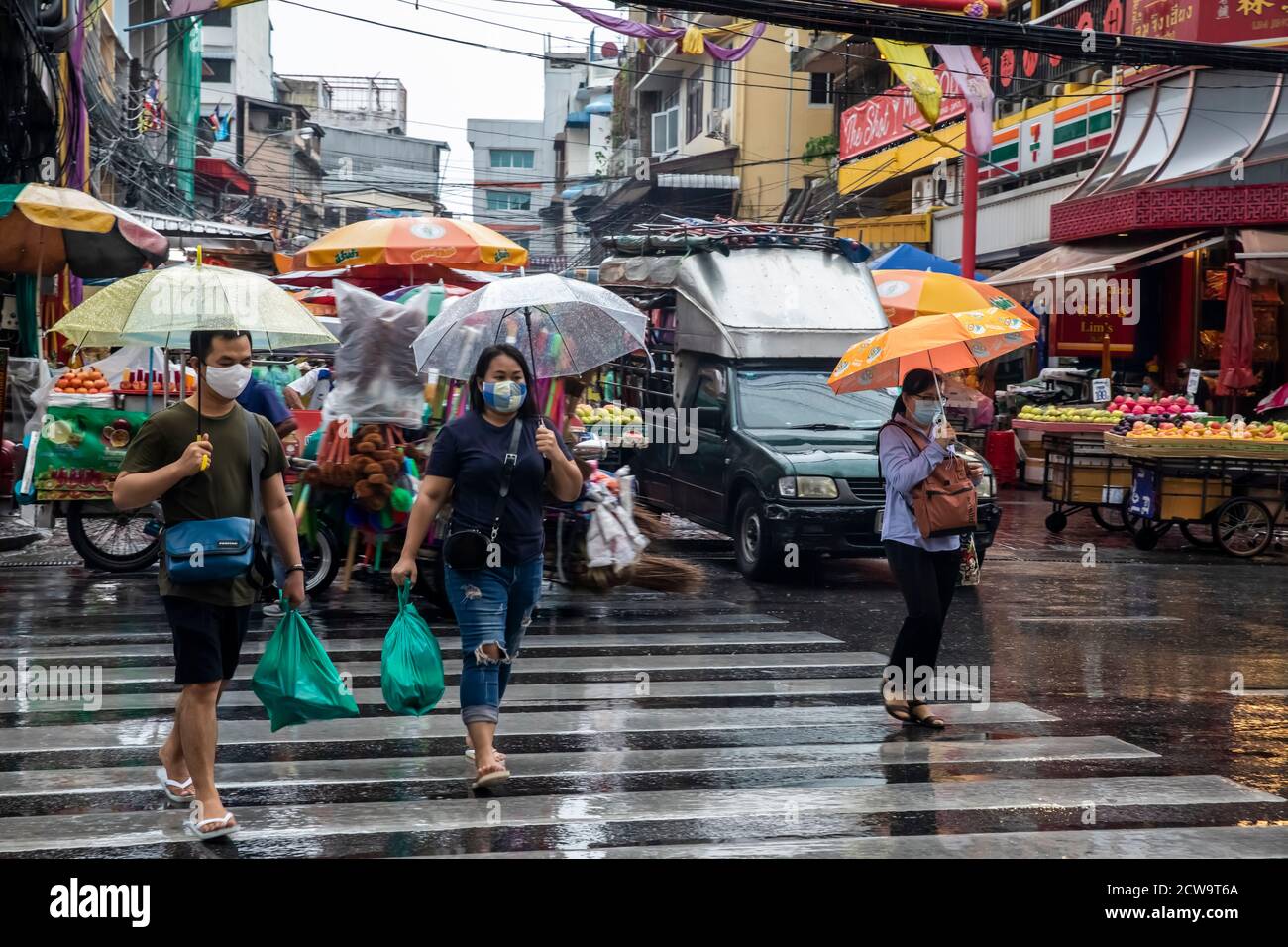 Les navetteurs défilent de l'autre côté de la rue pour commencer leur trajet pluvieux à la maison après des travaux dans le quartier chinois de Bangkok. Banque D'Images