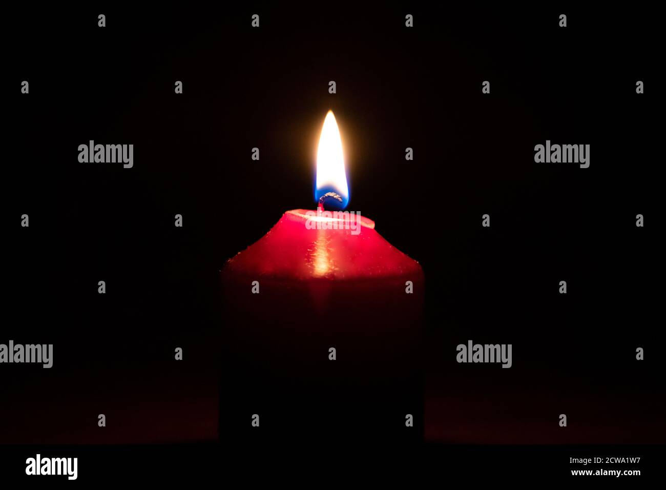 Une bougie rouge allumée illumine les darknes avec la bougie flamme légère et feu comme macro gros plan dans la nuit et affiche une atmosphère romantique Banque D'Images