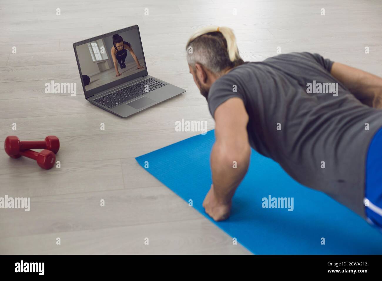 Taille basse non reconnaissable debout dans Plank pose en regardant la vidéo sur ordinateur portable Banque D'Images