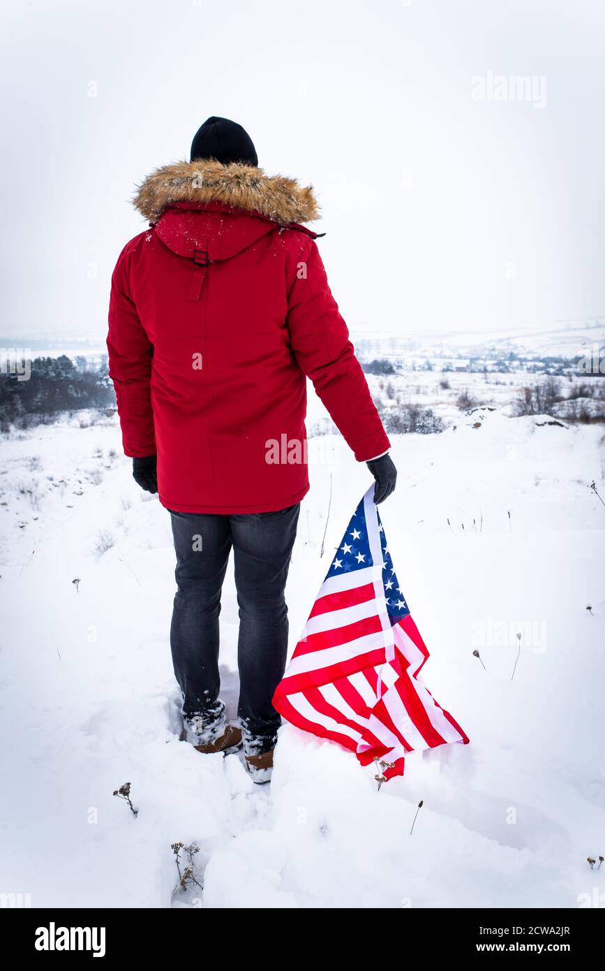 L'homme en manteau d'hiver rouge holding usa flag par temps de neige Photo  Stock - Alamy