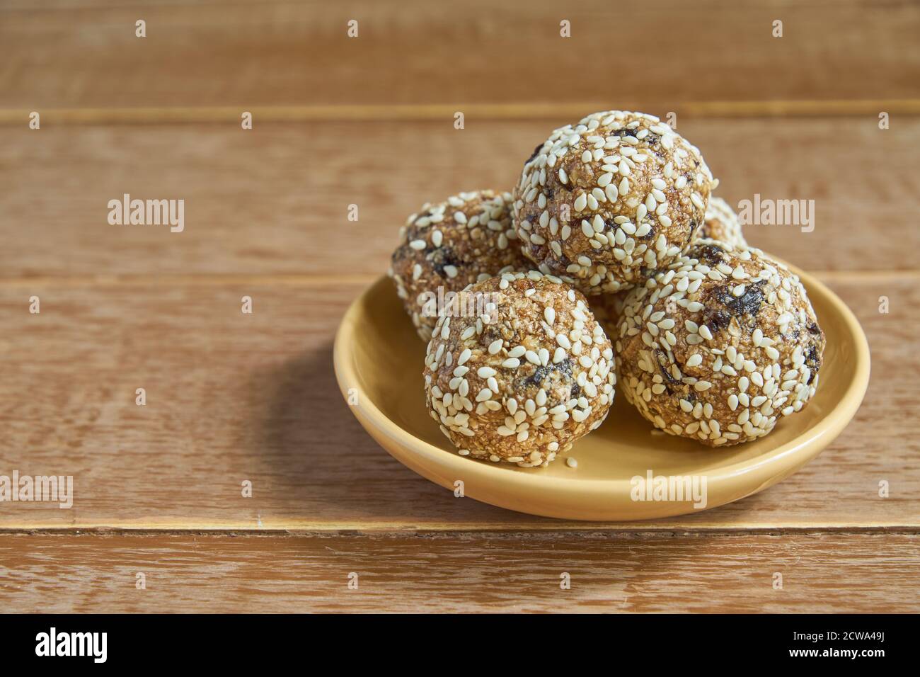 Boulettes de protéines de sésame d'Oatsmeal. Bouchées à faible teneur en matières grasses avec flocons d'avoine, noix de sésame et pruneaux sur fond de bois Banque D'Images