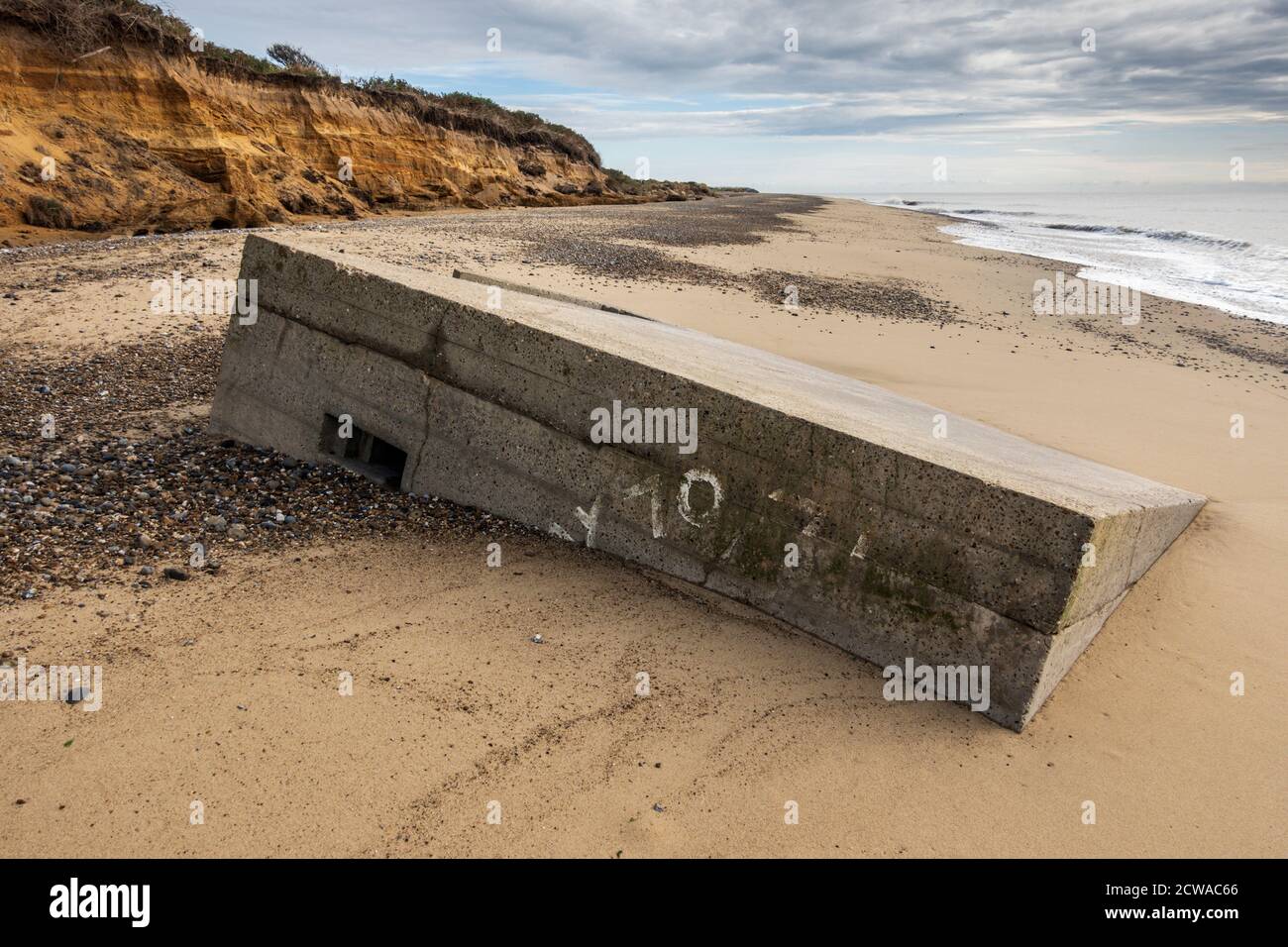 La deuxième Guerre mondiale pilbox qui était autrefois sur le sommet de la falaise et maintenant due à l'érosion côtière est sur la plage en dessous, Benacre, Suffolk, Angleterre. Banque D'Images