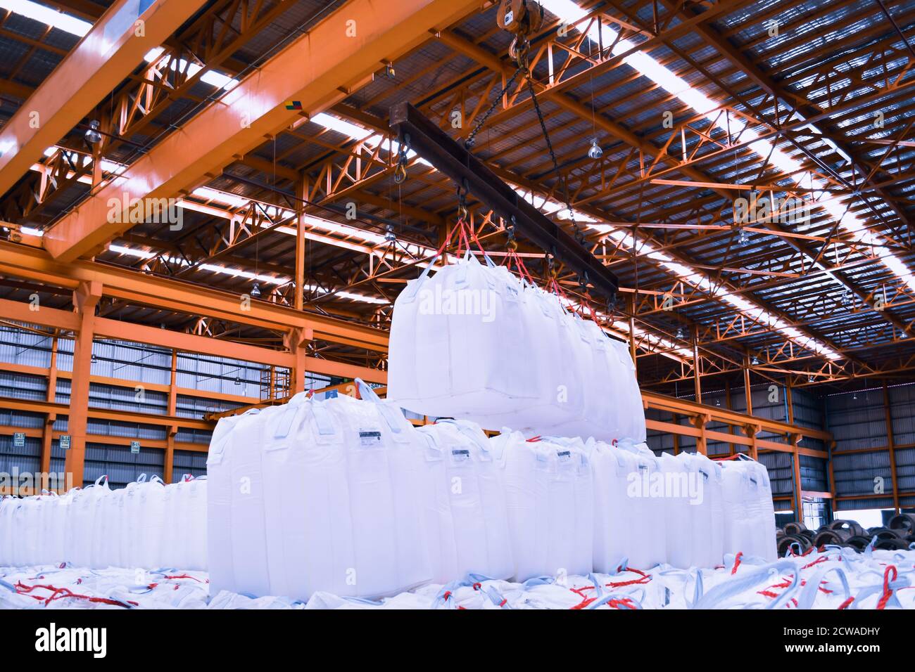 Un pont roulant lève les sacs géants de tapioca à l'aide d'une barre de répartition dans l'entrepôt de stockage. Chargement en vrac dans un équipement de manutention de sacs jumbo. Banque D'Images