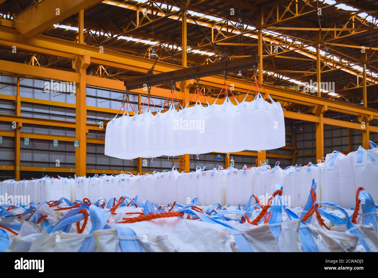 Un pont roulant lève les sacs géants de tapioca à l'aide d'une barre de répartition dans l'entrepôt de stockage. Chargement en vrac dans un équipement de manutention de sacs jumbo. Banque D'Images
