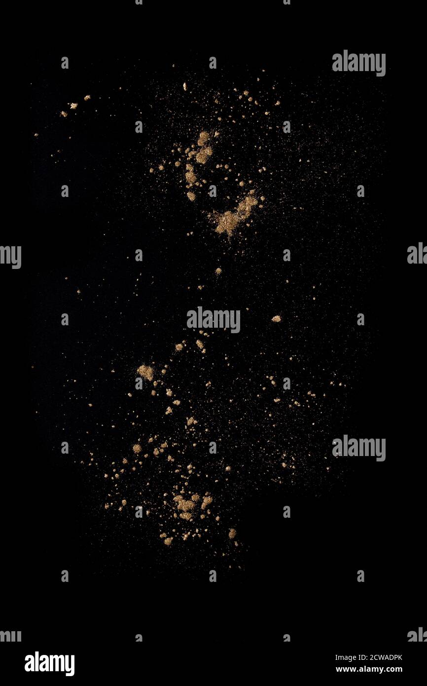 Les poudres dorées éclabousser et dépoussiérer le noir. Arrière-plan de conception abstrait Banque D'Images