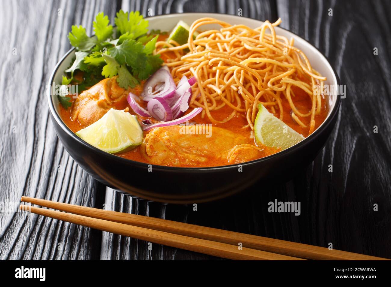 Le Khao soi est un plat de nouilles au curry jaune crémeux, légèrement épicé, que l'on trouve dans le nord de la Thaïlande, dans le bol de la table. Horizontale Banque D'Images