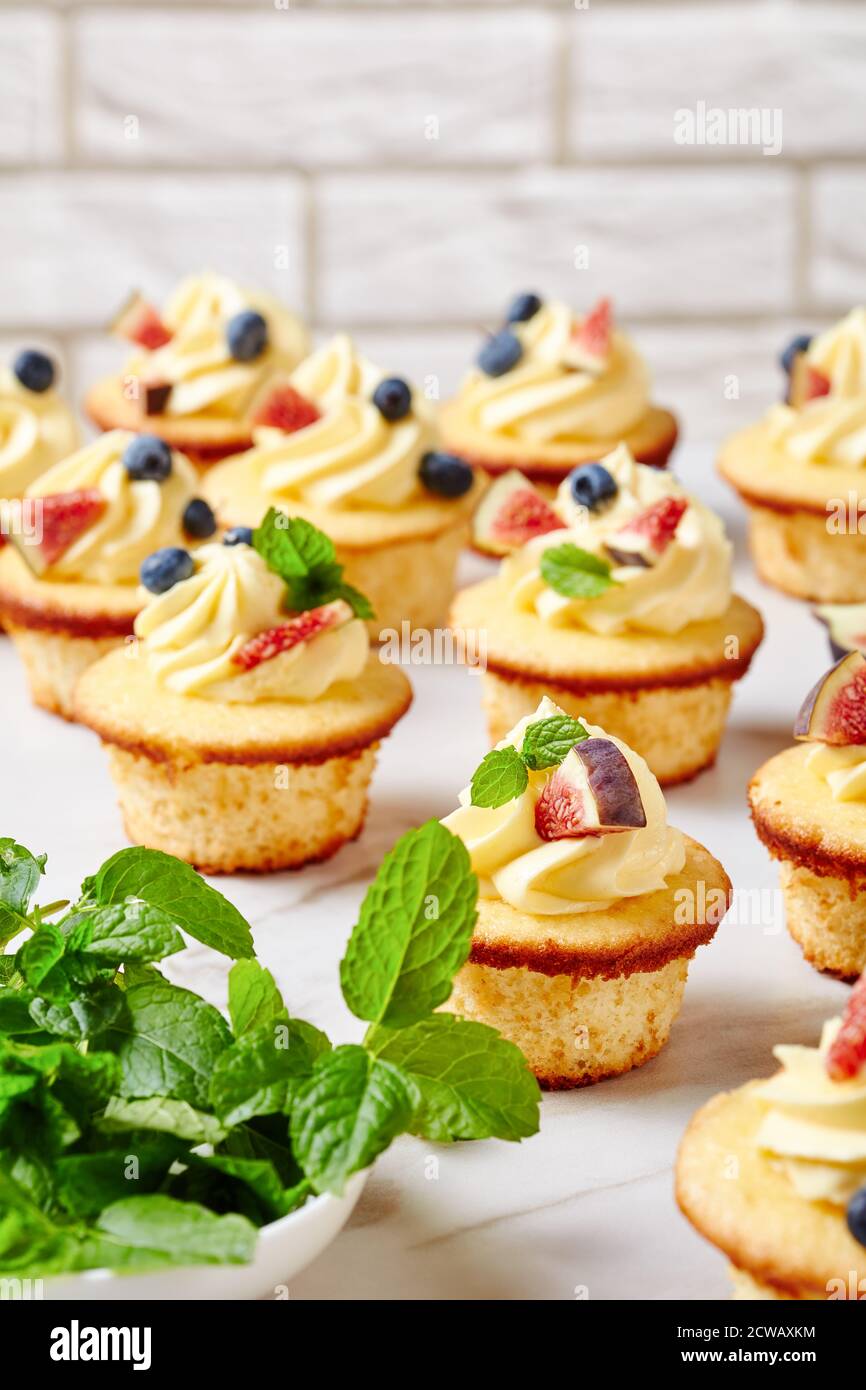 délicieux petits gâteaux à la crème de beurre et aux baies fraîches et à la menthe sur une table en marbre, vue verticale d'en haut, gros plan Banque D'Images