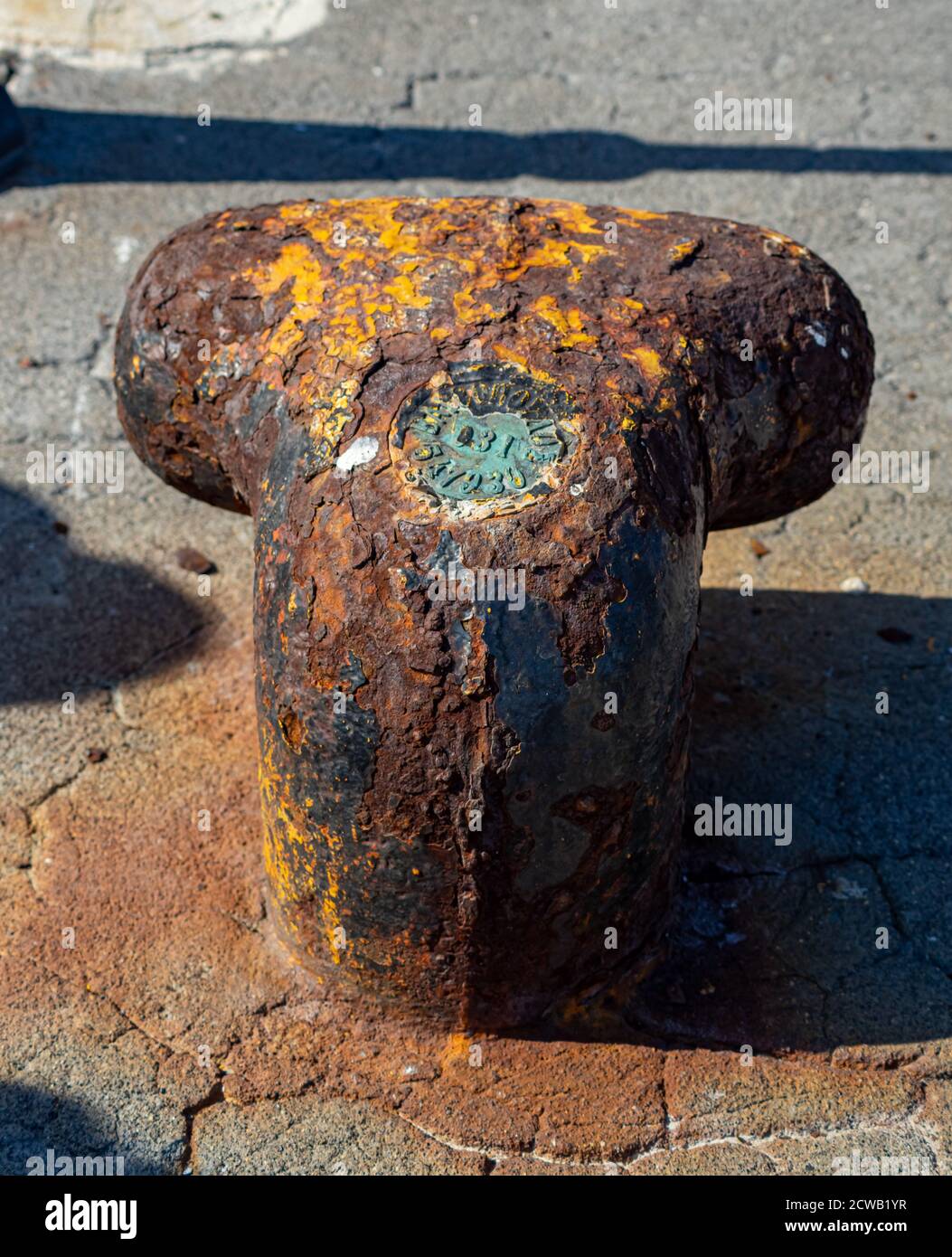 Gros plan d'un ancien poste de mouillage rouillé sur le front de mer dans une petite marina, élément pour amarrer les navires dans le port, sécurité Banque D'Images