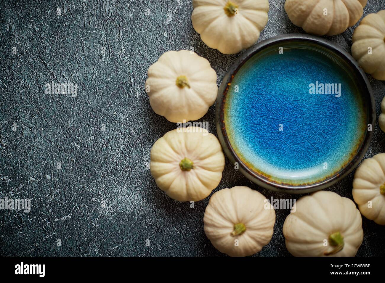Mini-citrouilles blanches mignonnes placées en cercle avec bol en céramique bleu au milieu Banque D'Images