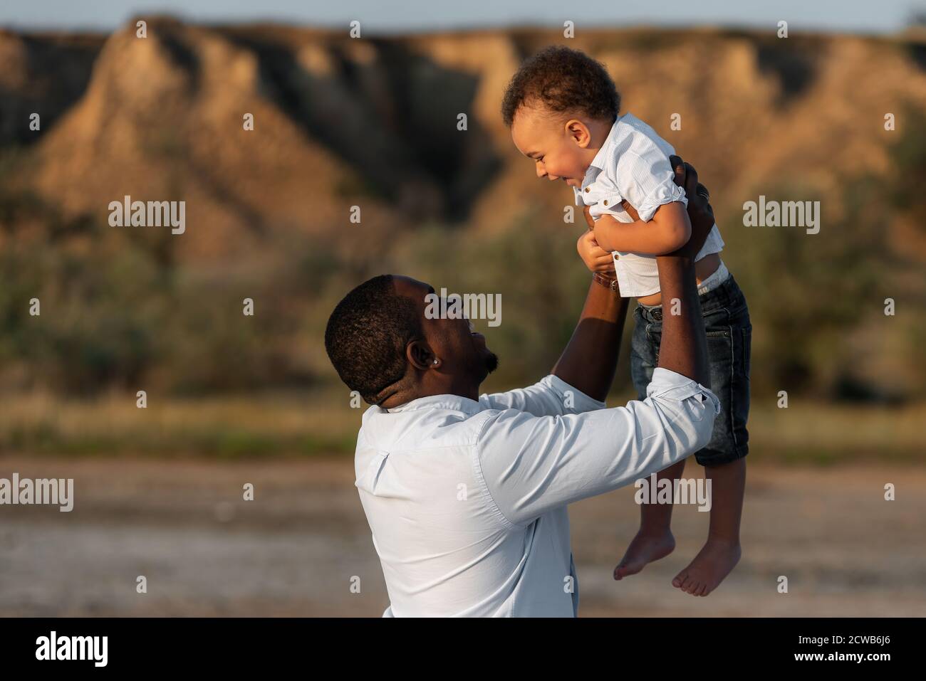 Joyeux père et fils afro-américains ayant un bon moment à l'extérieur. Père ayant le plaisir jette dans l'air son enfant. Concept de fête des pères heureux. Banque D'Images