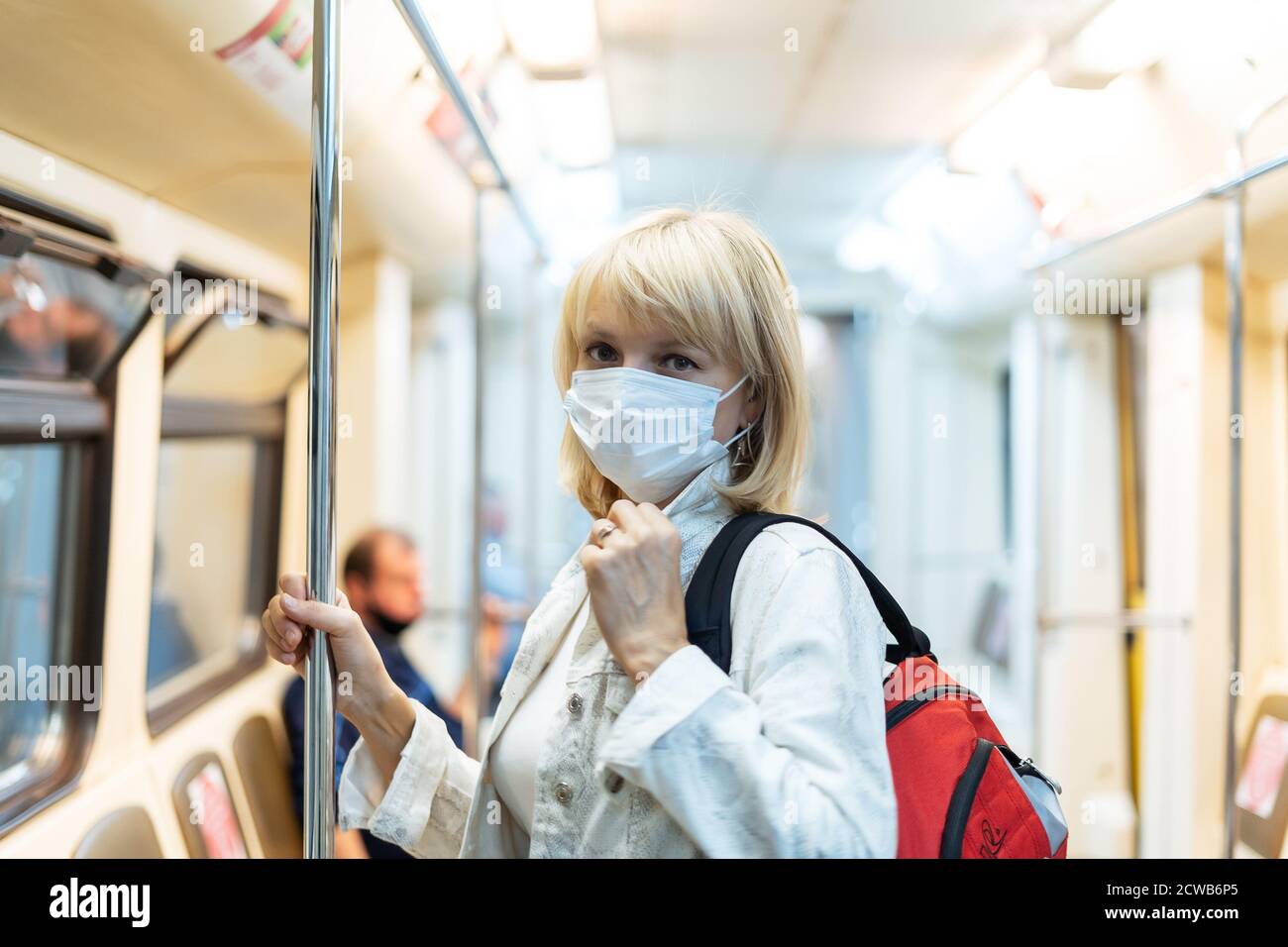 Portrait de la belle femme adulte dans le masque médical de protection avec le sac à dos se trouve dans le métro et regarde l'appareil photo Banque D'Images