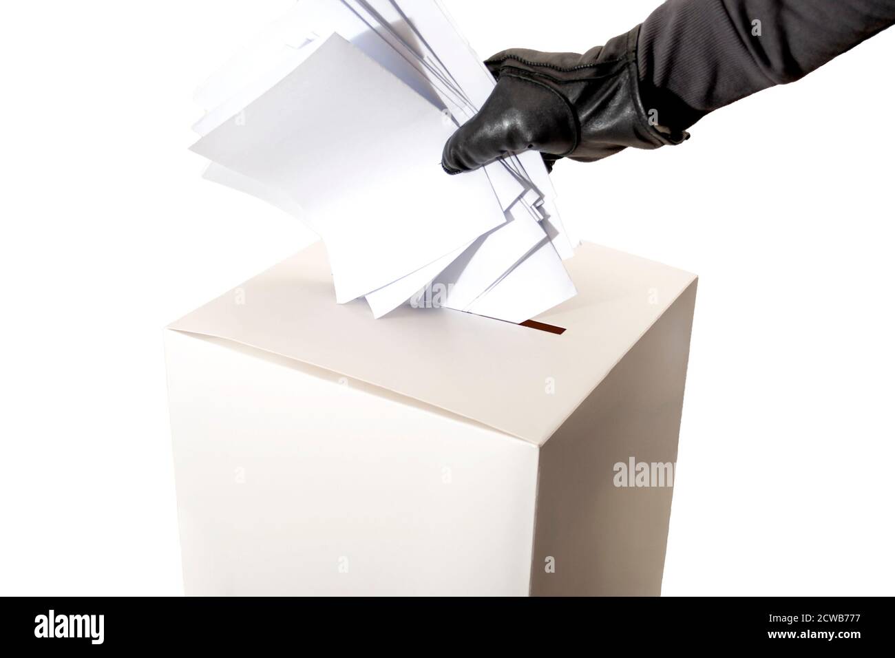 Fraude électorale et élections piratées concept avec une main portée un gant en cuir et rembourrage d'une boîte de vote isolée sur arrière-plan blanc avec fonction de copie Banque D'Images
