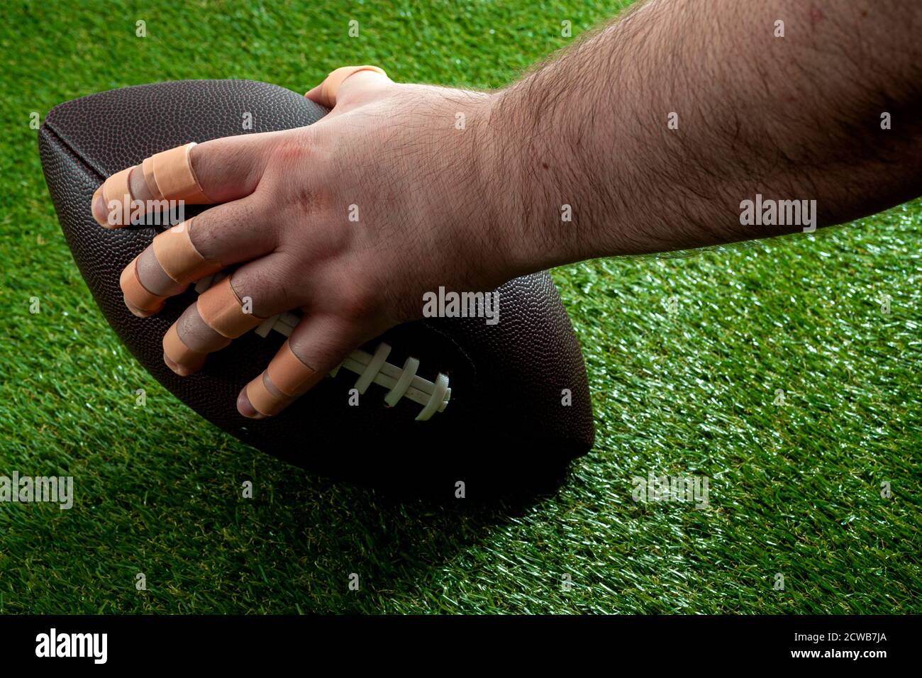 Un match de football américain de nuit sous la lumière de l'idée conceptuelle avec une main de lineman offensant avec des doigts bandés tenant la balle et obtenir de l'rea Banque D'Images