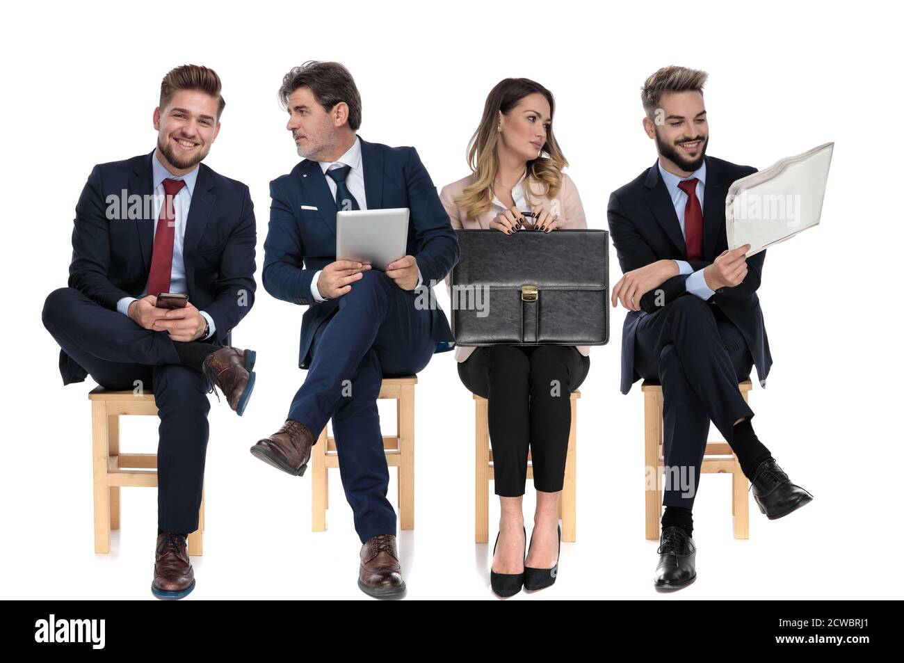 Équipe de 4 hommes d'affaires tenant, téléphone, table, journal et mallette en attendant un entretien d'emploi assis sur des chaises sur fond blanc studio Banque D'Images