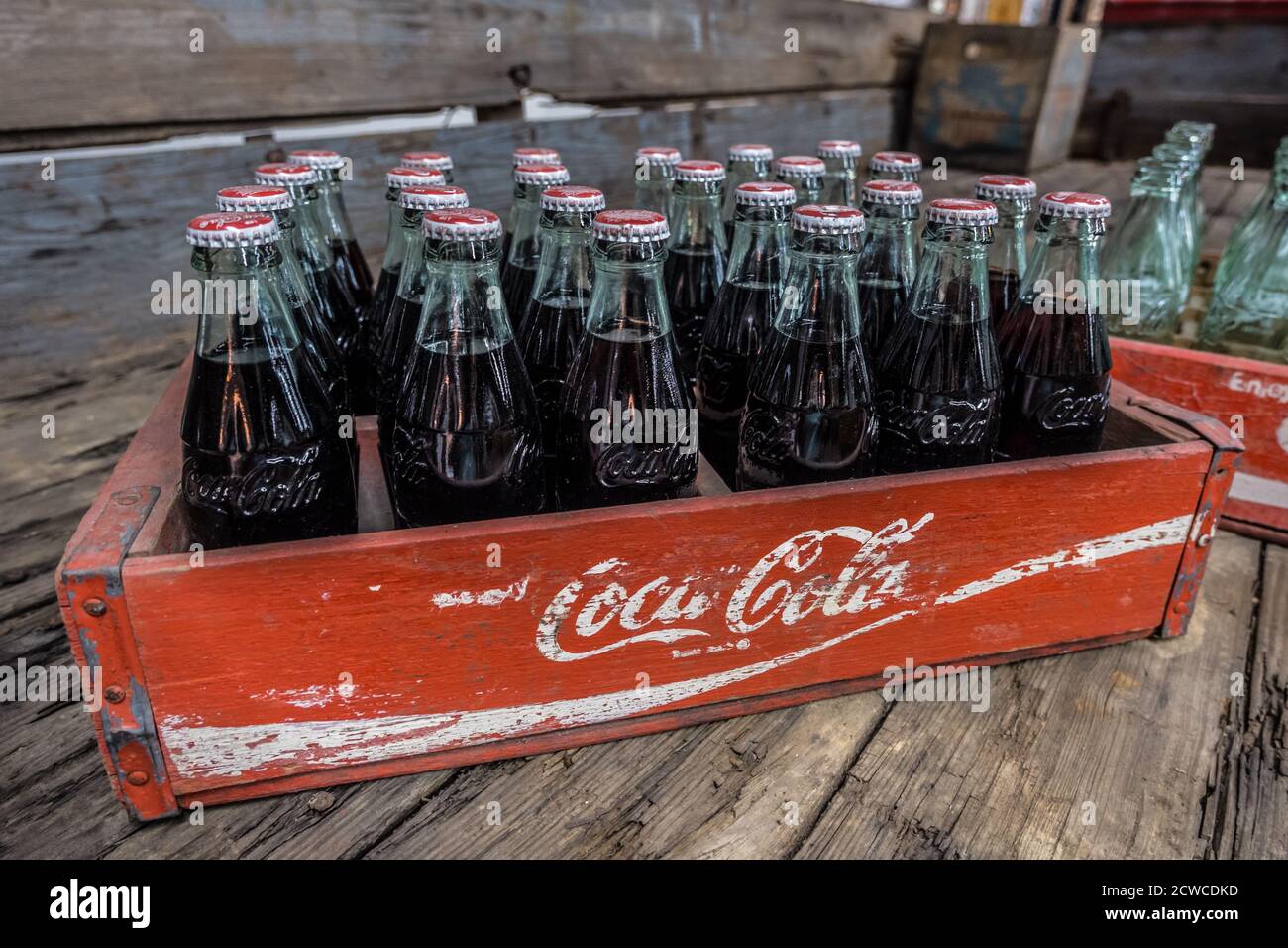 Coca-Cola vintage avec cola encore dans les bouteilles de verre dedans une caisse de livraison en bois sur un vieux plancher en bois à l'intérieur, en gros plan Banque D'Images