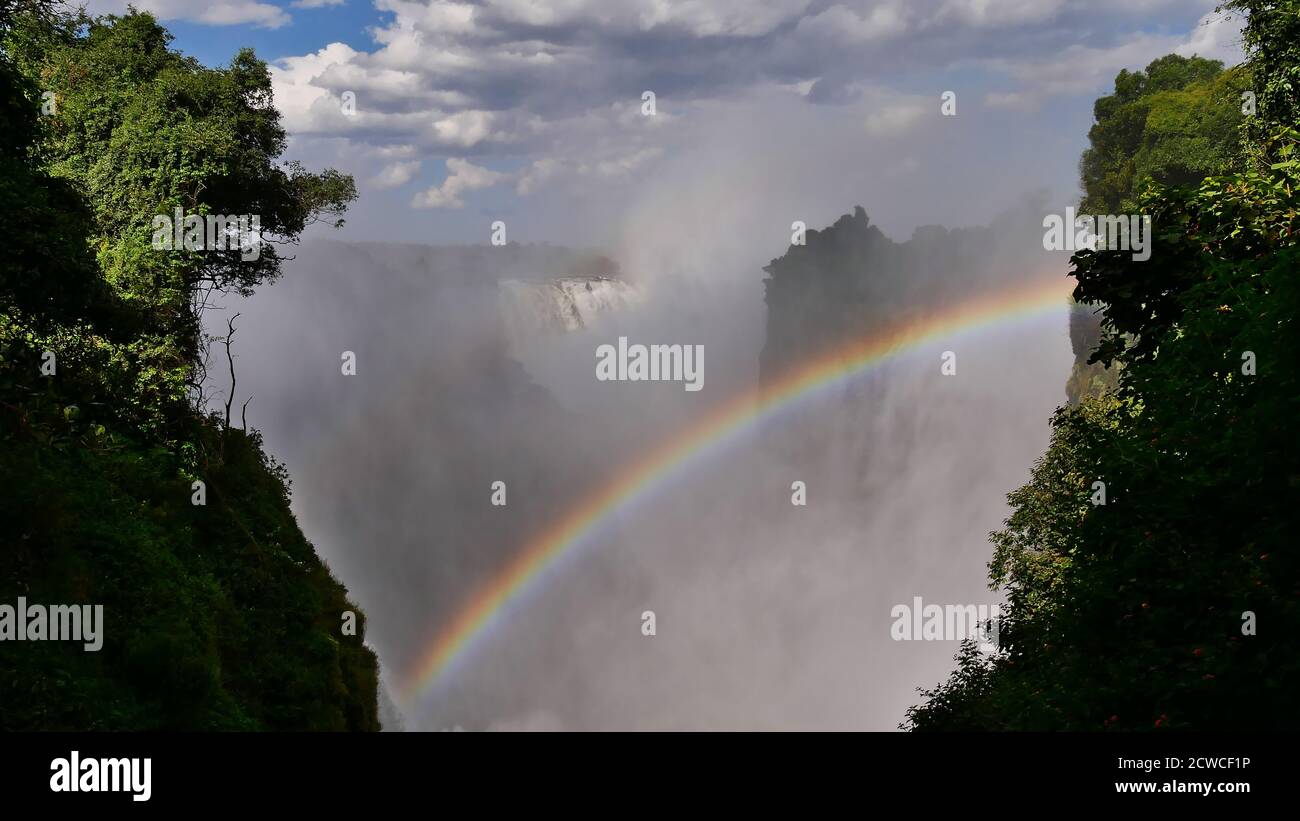 Vue imprenable sur la puissante rivière Zambesi qui descend les chutes Victoria depuis la direction ouest avec un jet énorme et un magnifique arc-en-ciel coloré. Banque D'Images