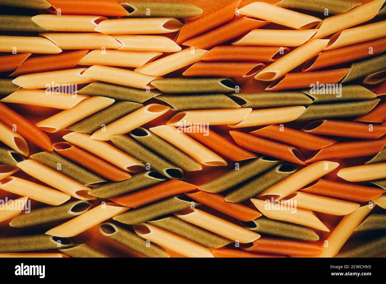 Cadre composé de pâtes vertes, jaunes et rouges de penne colorées naturellement avec de la tomate et des épinards. Concept des produits non périssables. Banque D'Images