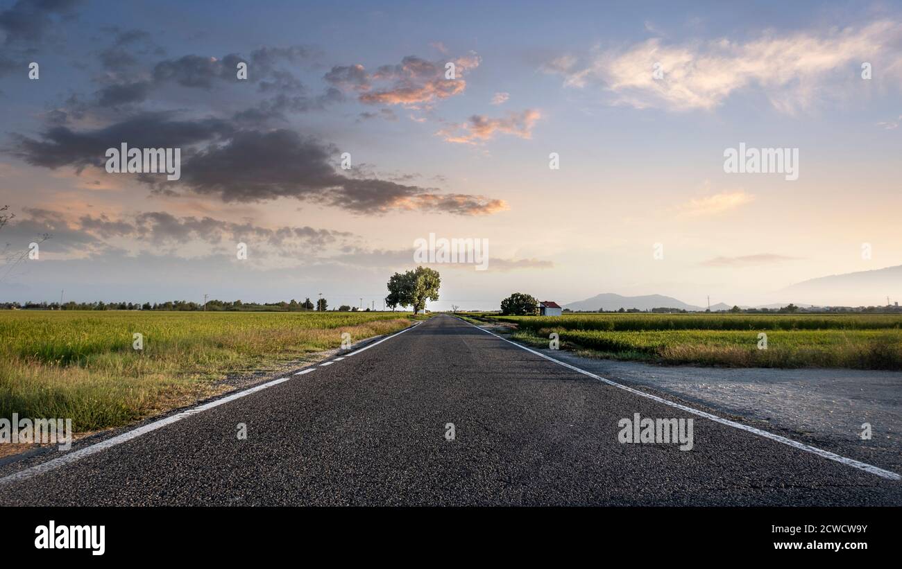 Panoramique d'une longue route d'asphalte vide vers le ciel du coucher du soleil. Espace de copie vide pour le contenu de l'éditeur. Banque D'Images