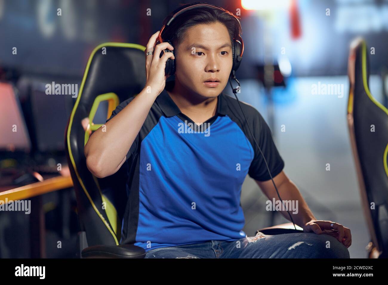 Portrait d'un homme asiatique confus, un gamer de cyber sport masculin portant un casque regardant l'écran d'un PC avec une triste expression du visage tout en participant à un tournoi eSports, jouant à des jeux vidéo en ligne Banque D'Images