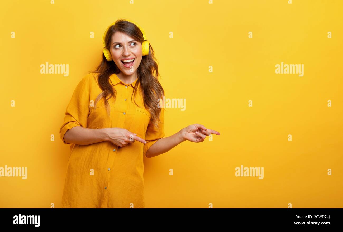 Fille avec casque jaune écoute de la musique et des danses. Expression émotionnelle et énergique. Banque D'Images