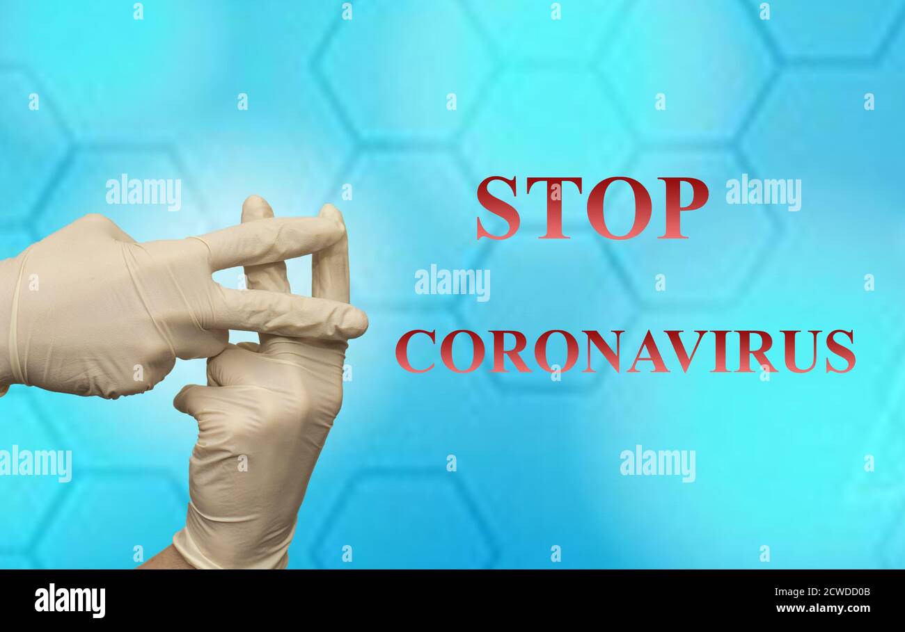 Gros plan de la main hashtag dans un gant en latex avec 'STOP Texte DU CORONAVIRUS contre un motif hexagonal Banque D'Images
