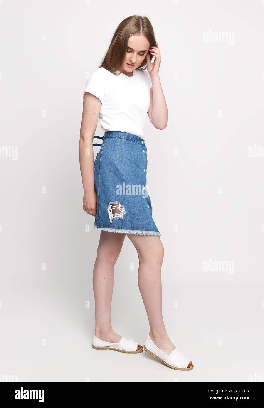 adorable jeune femme mince dans un t-shirt blanc et jupe tendance en denim sur fond blanc. concept de publicité photo pour une fois Banque D'Images