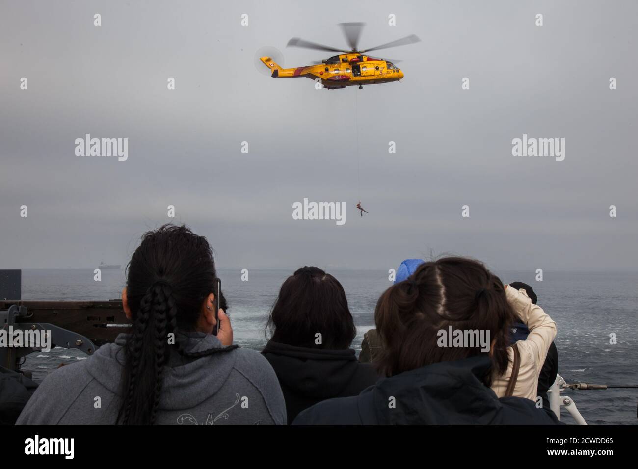 À bord d'un navire de guerre de la base des Forces canadiennes à Esquimalt, en Colombie-Britannique, un groupe de femmes regarde une démonstration de recherche et de sauvetage d'un CS Banque D'Images